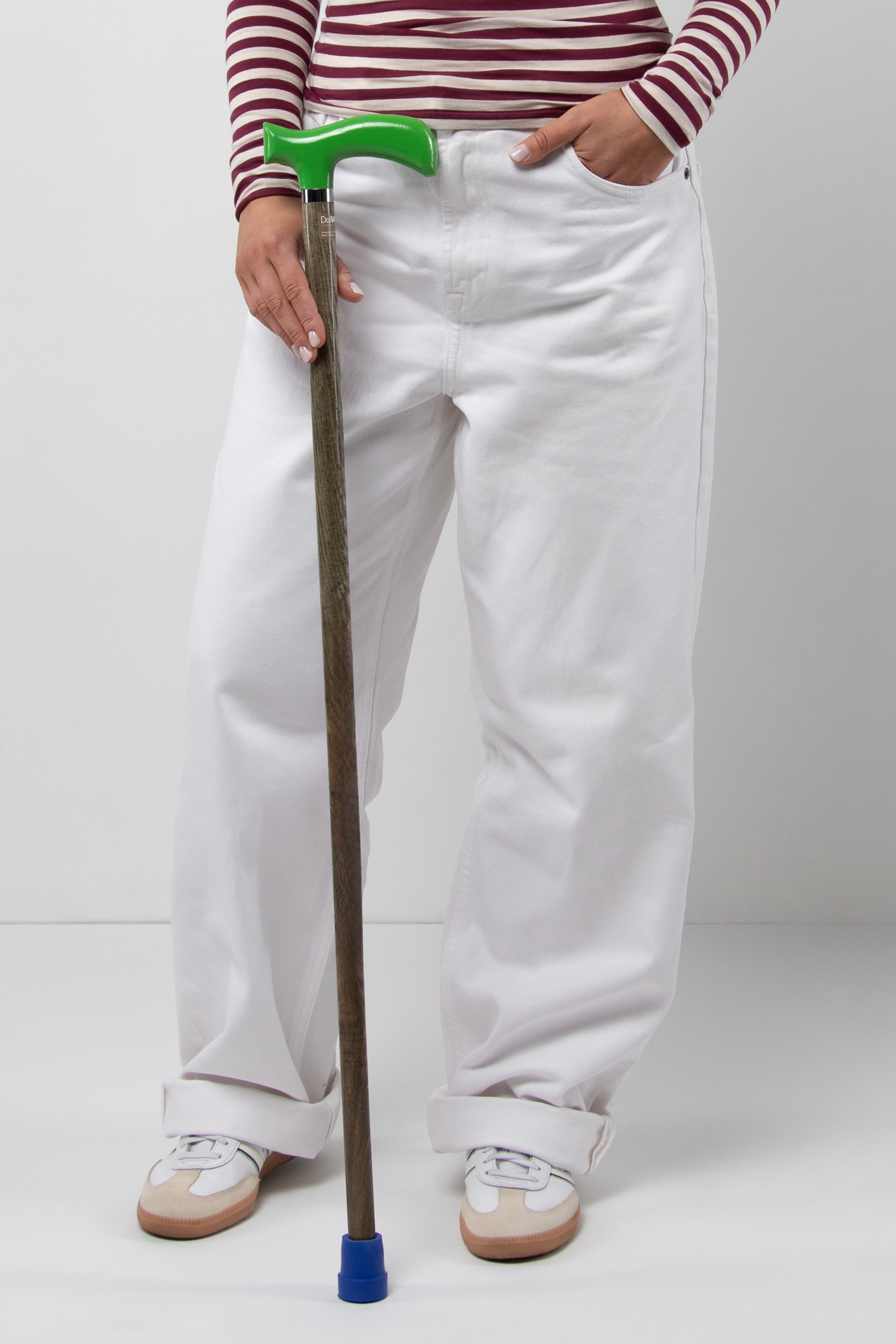 Active young woman's walking cane with traffic green handle and light oak wood shaft. Stable custom length mobility aid for daily support.