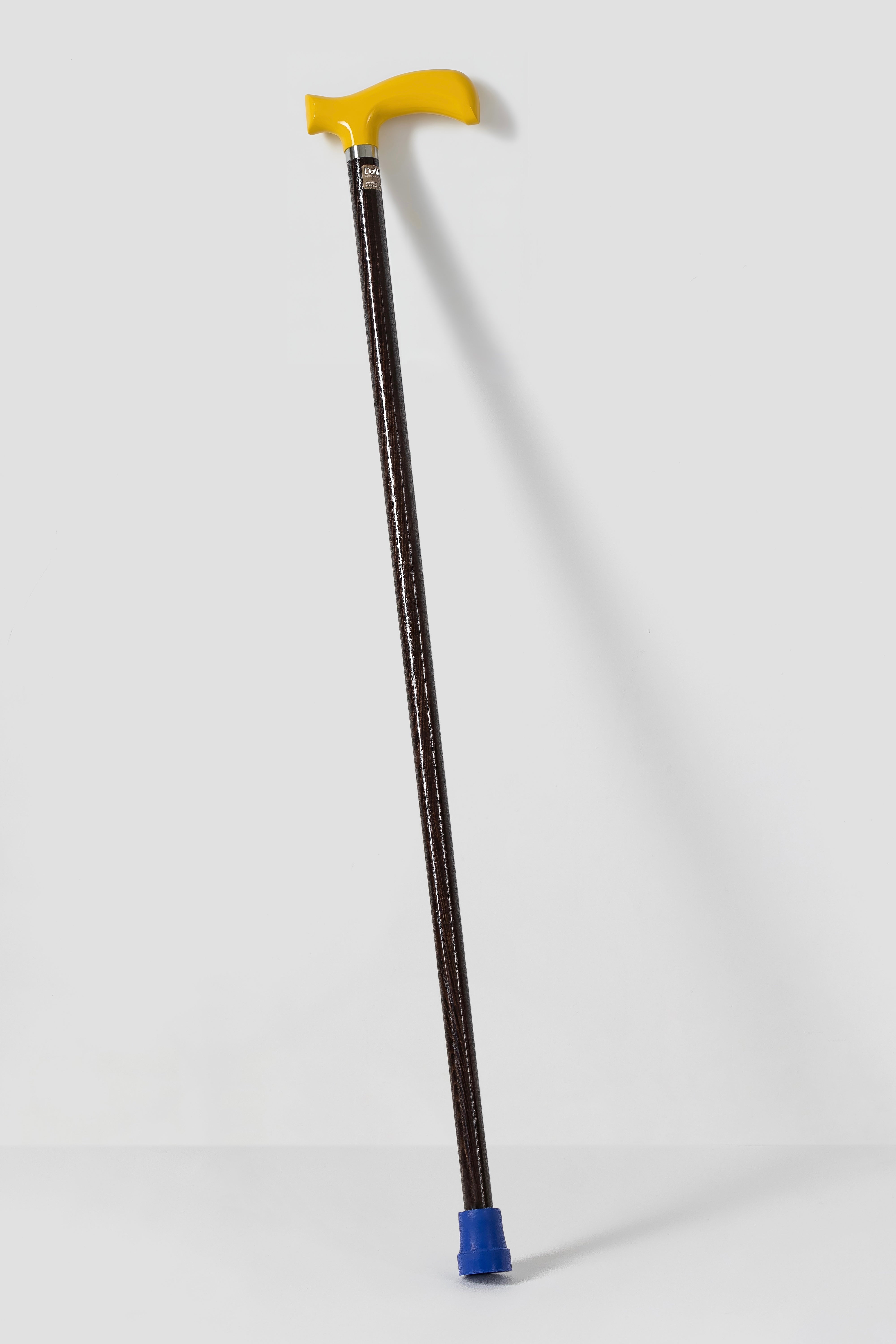Bright yellow ergonomic walking stick on dark stained oak. Custom made premium cane for daily stability.