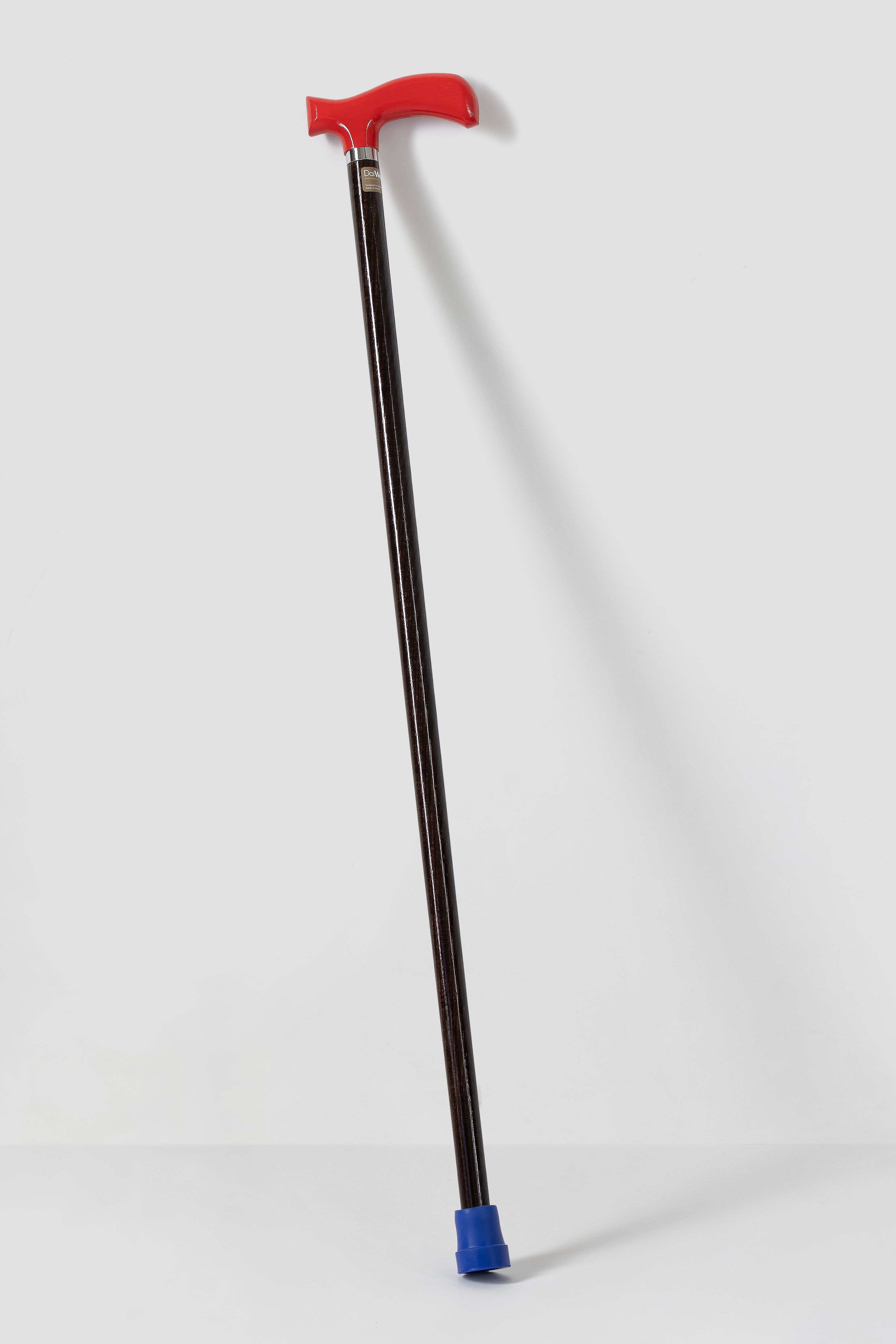 Crimson red ergonomic walking stick on dark oak. Luxury handmade designer cane for professional support.