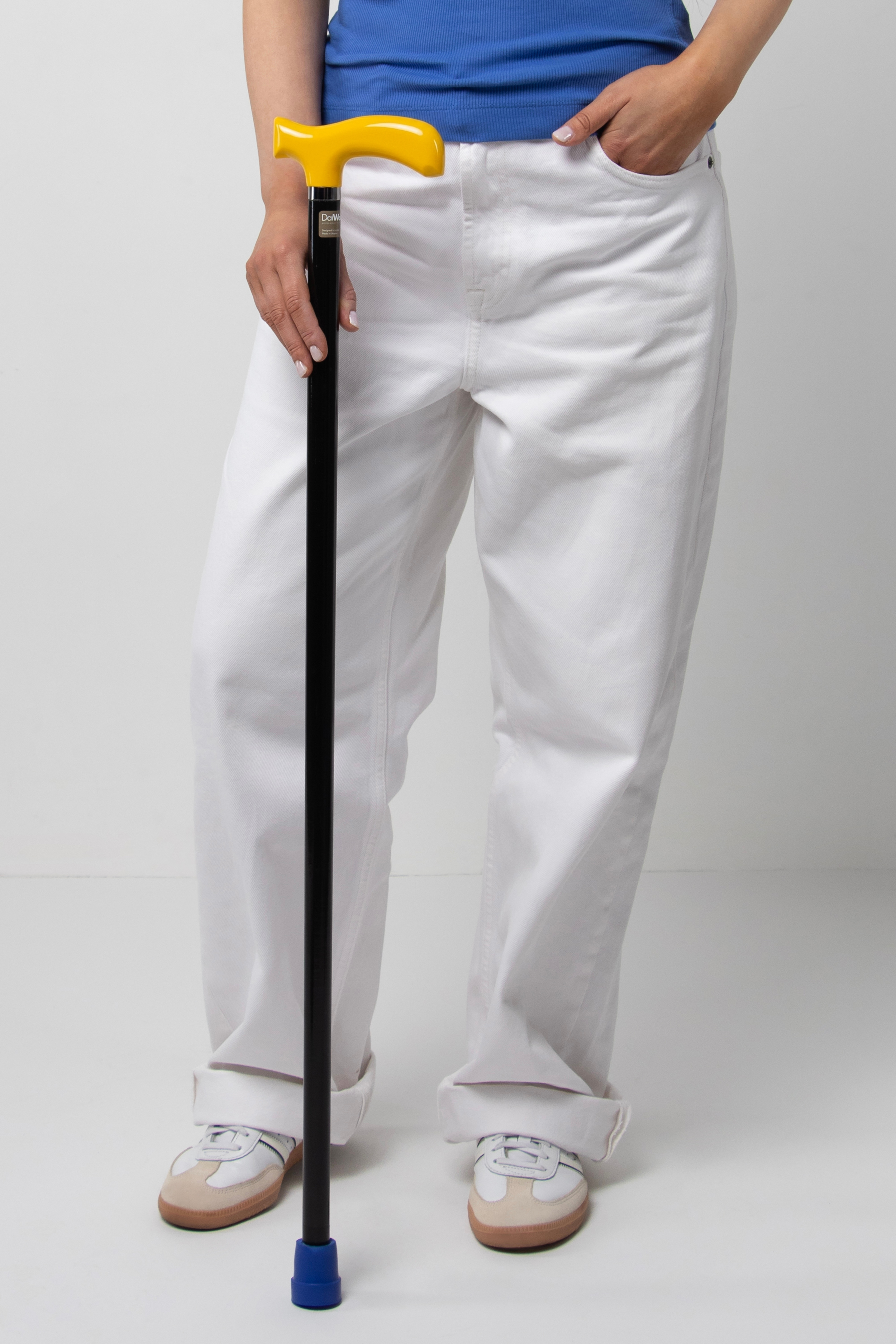 Modern women's designer walking cane with yellow handle and solid black shaft. Urban style ergonomic aid for active seniors and adults.